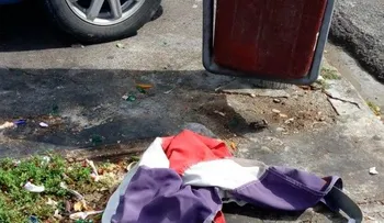 Tiran bandera Nacional al lado de un zafacón en la Ortega y Gasset