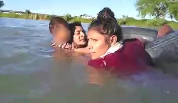 Un niño se aferra a un neumático mientras cruza junto a sus padres a EEUU por el río Bravo