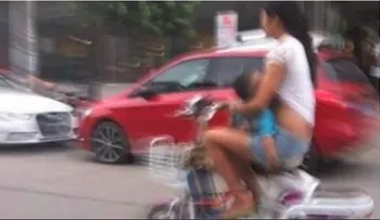 Amamanta a su hijo mientras conduce un ciclomotor