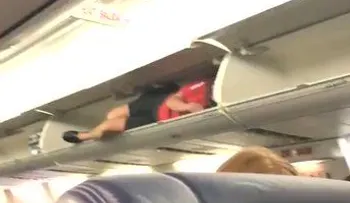 Una azafata se mete en compartimiento equipajes de un avión para hacer reír a los pasajeros