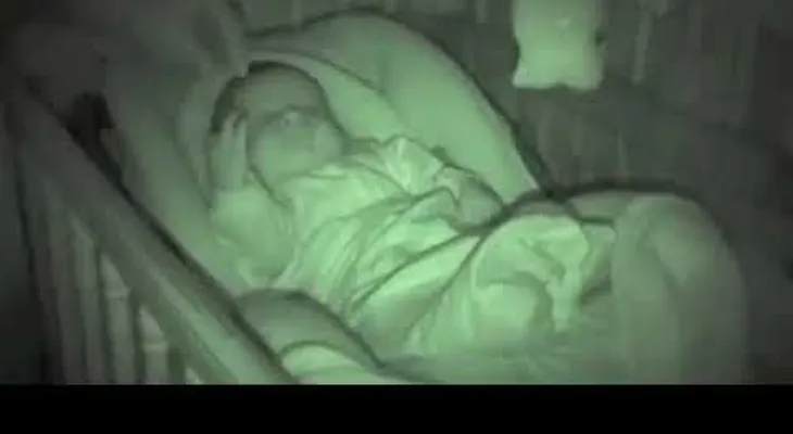 El papá coloca pone las manos del bebé bajo la manta, y la cámara de la niñera ha hecho reír a todos 