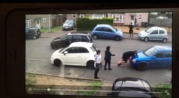 Desplaza con sus manos el coche de su vecino para que pase el de su tía