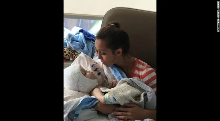 Madre carga a uno de los gemelos separados por primera vez