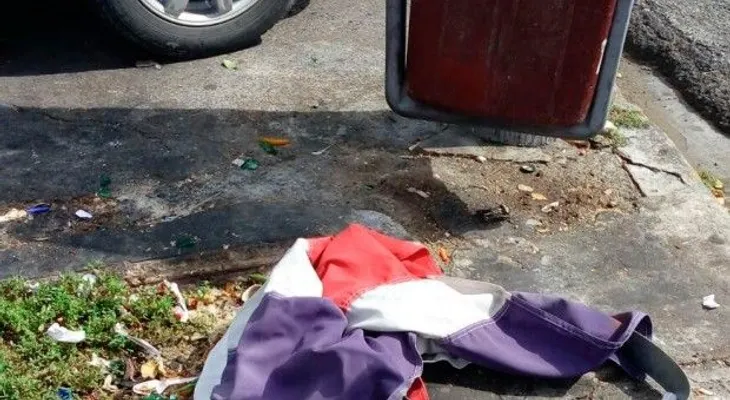 Tiran bandera Nacional al lado de un zafacón en la Ortega y Gasset