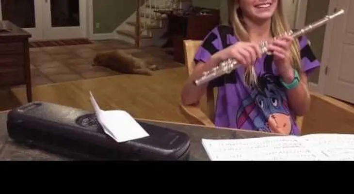 La niña quiere practicar flauta, pero un perro gruñón no parece gustarle la idea 