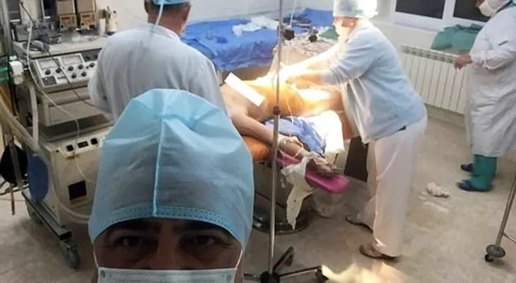 Médico toma selfie con la nueva madre desnuda en el fondo