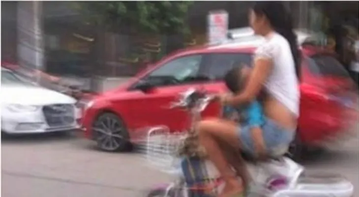 Amamanta a su hijo mientras conduce un ciclomotor